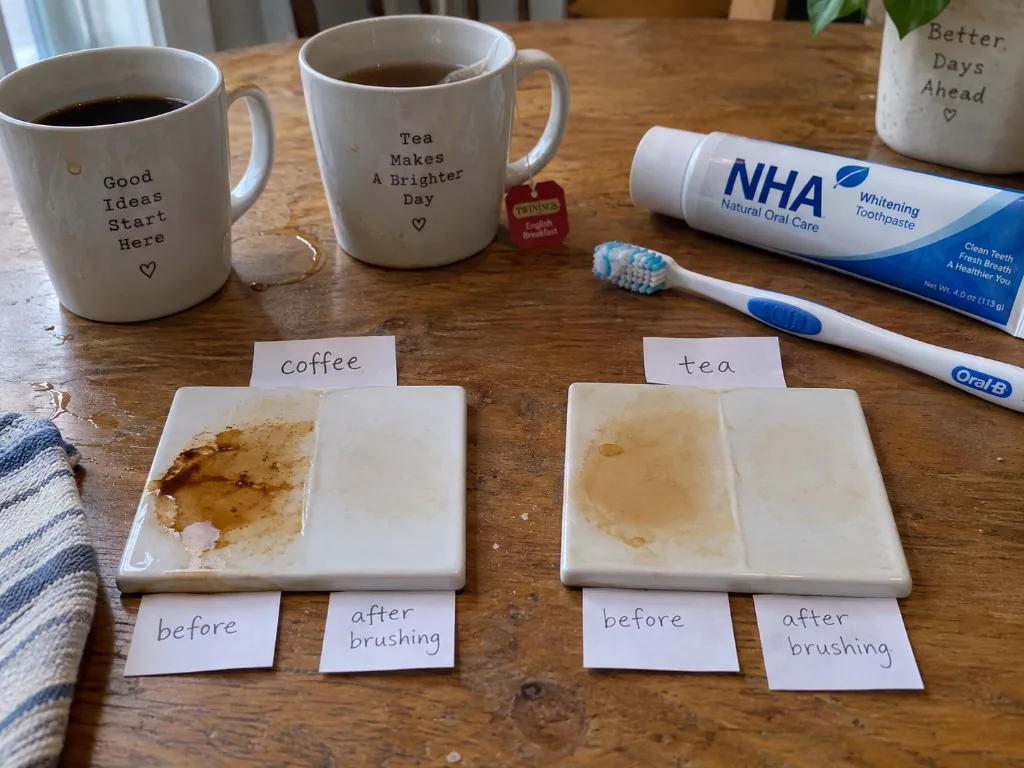 Nano-hydroxyapatite toothpaste stain wipe on a wood table: coffee tile split before and after brushing, black tea tile split before and after brushing, with the nHA tube and an Oral-B brush